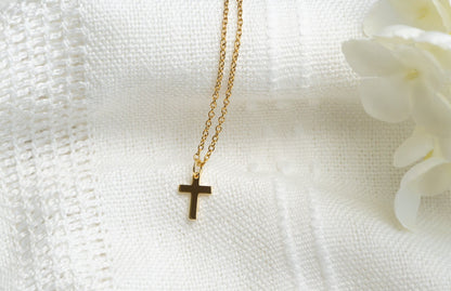 Gold cross necklace on a white textured fabric background
